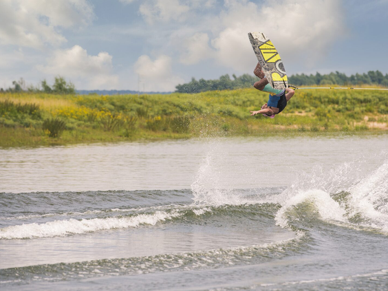 Persoon aan het wakeboarden op de Nederrijn bij Vakantiepark Bad Nederrijn, een perfecte locatie voor watersport met het gezin in Gelderland.