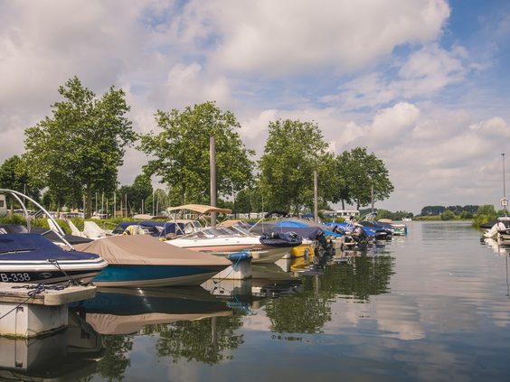 De gezellige jachthaven van Vakantiepark Bad Nederrijn, vol met plezierboten en zeilbootjes aan de steigers.