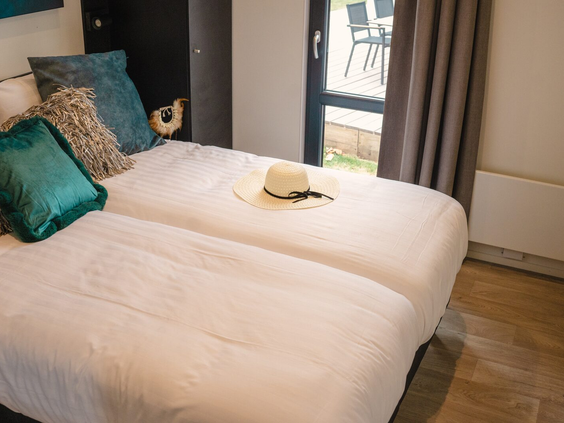 Comfortabel opgemaakt tweepersoonsbed in een slaapkamer van een vakantiehuis op Vakantiepark Bad Nederrijn.