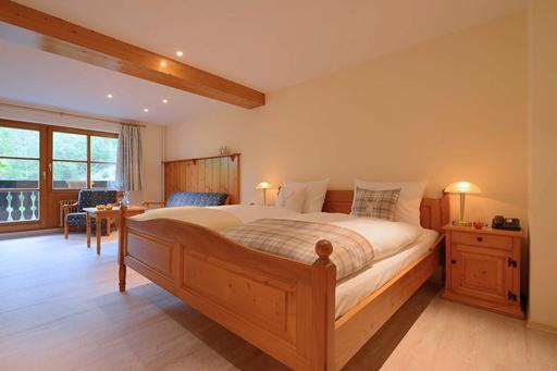 De sfeervolle en ruime familiekamer van hotel Hofgut Sternen, ingericht met veel hout voor een authentieke sfeer.