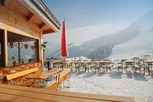 Een zonnig, besneeuwd terras van een berghut met uitzicht op de skipistes en bergen van het Zwarte Woud.