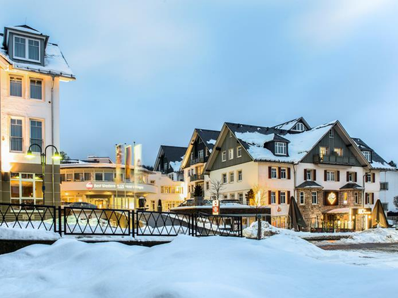 De sfeervol verlichte buitenkant van het Best Western hotel en appartementen in Willingen, bedekt met een dik pak sneeuw in de avond.