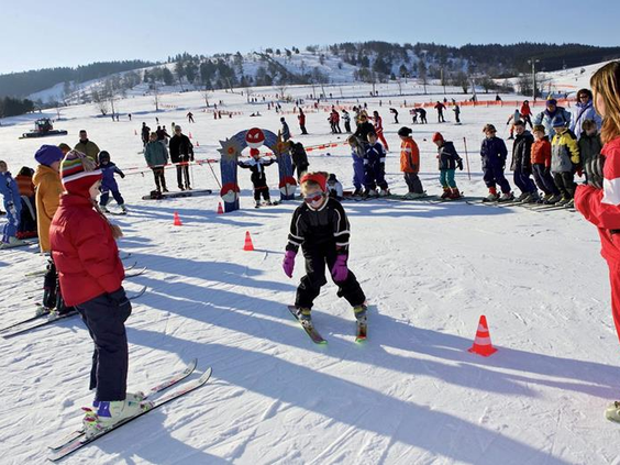 Kinderen leren skiën op de oefenweide in Willingen, waar ze slalommen tussen de pionnen tijdens de skiles.