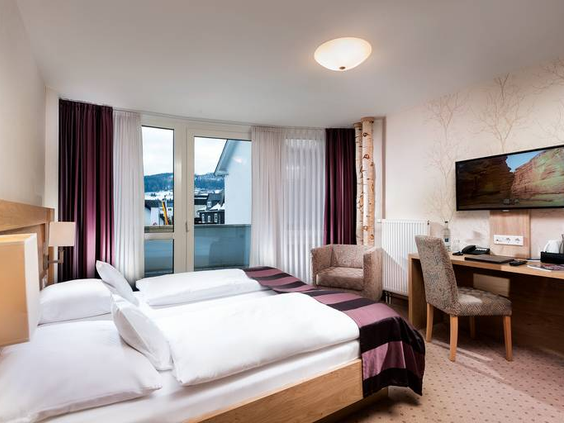 Een lichte en comfortabele hotelkamer in het Best Western Willingen, met fris opgemaakte bedden en een deur naar het balkon.