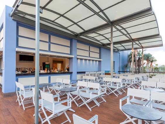 Het gezellige, overdekte buitenterras van een van de bars bij Blue Lagoon Resort, met witte tafels en stoelen