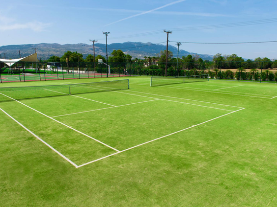 De groene tennisbaan van Blue Lagoon Resort op Kos, gelegen in een groene omgeving met bergen op de achtergrond.