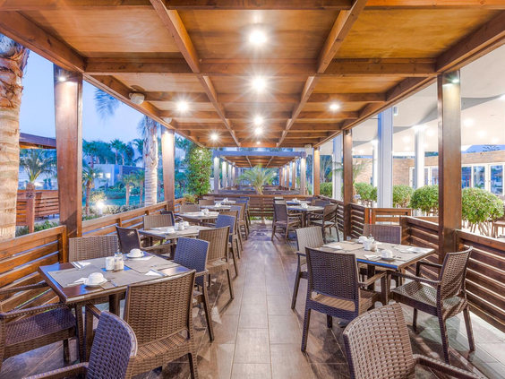 et sfeervol verlichte buitenterras van een restaurant bij Blue Lagoon Resort, met een houten overkapping en gedekte tafels.