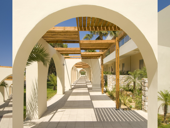 De prachtige architectuur van Blue Lagoon Resort, met een lang wandelpad vol witte bogen en houten pergola's die voor schaduw zorgen.