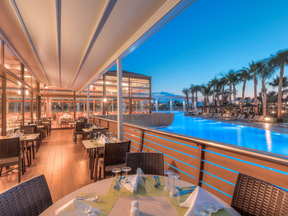 Het restaurantterras van Blue Lagoon Resort 's avonds, met een prachtig uitzicht over het blauw verlichte zwembad.