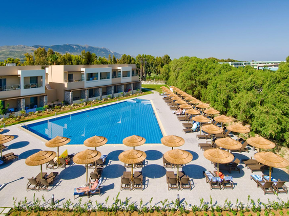 Een van de rechthoekige zwembaden van Blue Lagoon Resort, met rijen ligbedjes en rieten parasols waar gasten van de zon genieten.