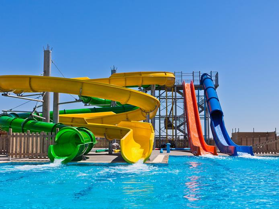 Het waterpark van Blue Lagoon Resort met verschillende snelle waterglijbanen, waaronder een gele en groene tunnelglijbaan en een steile blauw-oranje glijbaan.