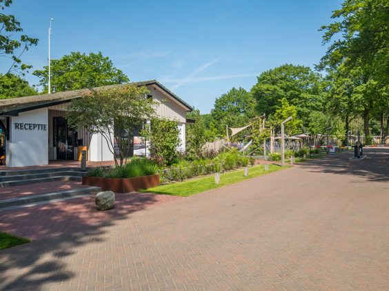 Hoofdgebouw en receptie van TopParken Bospark Ede met parkeerplaats