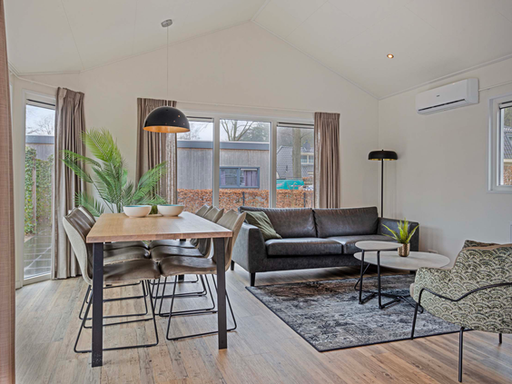 Moderne woonkamer van de 5-persoons Ferox XL bungalow op Bospark Ede, met een ruime zithoek en eettafel.