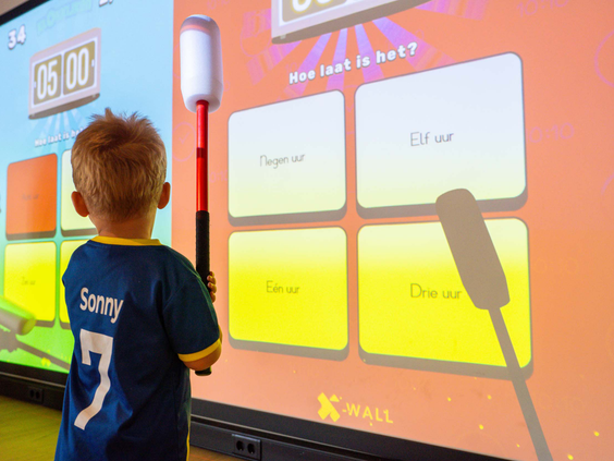 Kind speelt een spel op een groot interactief scherm in de speelhal