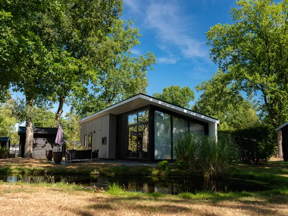 Een luxe, moderne vakantiewoning met een grote glazen pui en terras, prachtig gelegen tussen de bomen op Bospark Markelo.