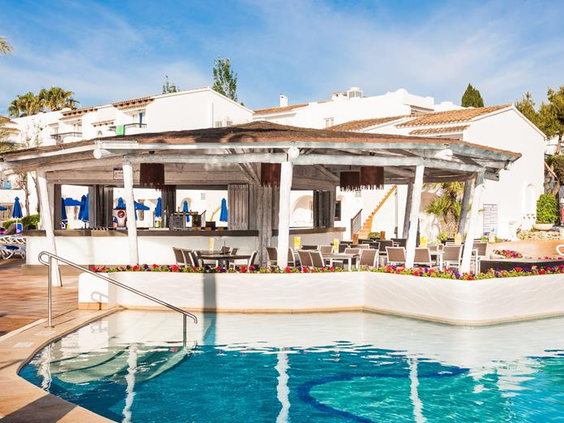 De gezellige, witgeverfde poolbar direct aan de rand van het zwembad, de ideale plek voor een hapje en drankje