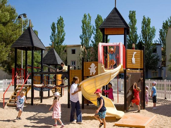Kinderen die vrolijk klimmen, klauteren en spelen in de uitgebreide houten speeltuin op een zandondergrond.