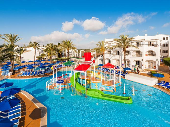 Kleurrijk kinderbad met een waterspeeltoestel, een groene glijbaan en een grote rode emmer die water omkiept voor extra spetterpret.