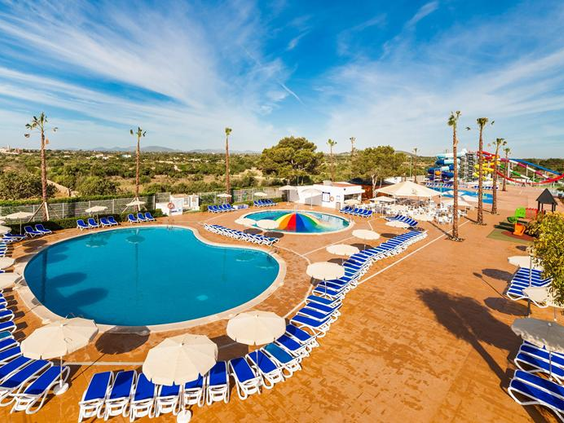 Rond zwembad met blauw-witte parasols en zonneterras bij Bouganvilla Hotel Appartementen Sa Coma Mallorca