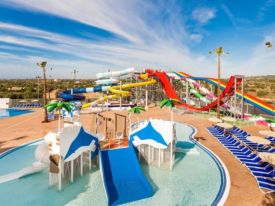 Het uitgebreide waterpark van Bouganvilla met diverse grote en snelle waterglijbanen, waaronder een rode, een regenboog- en een blauwe glijbaan.