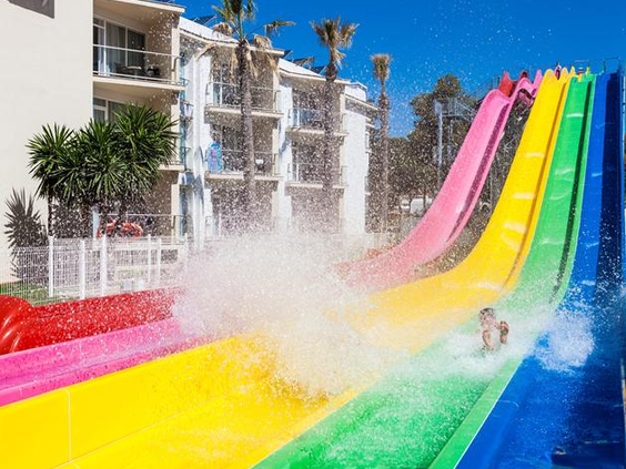 Kleurrijke regenboog waterglijbanen met spetterend water bij Bouganvilla Hotel Appartementen Sa Coma Mallorca