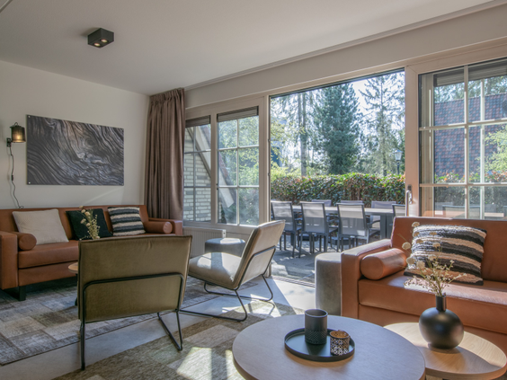 Stijlvolle en lichte woonkamer van een vakantiehuis op De Katjeskelder met uitzicht op de bossen.