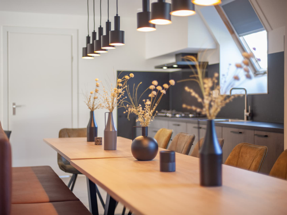 Moderne eethoek met lange houten tafel en open keuken in een accommodatie op De Katjeskelder.
