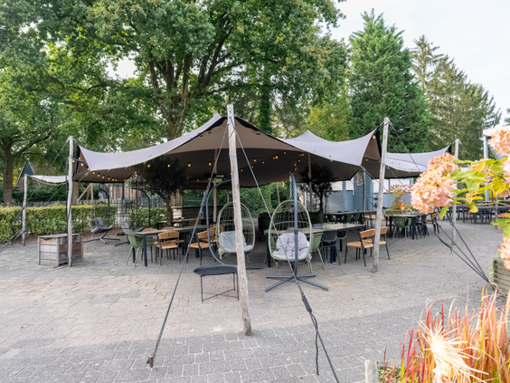 Groot buitenterras met sfeervolle overkapping en zitjes op vakantiepark De Katjeskelder.