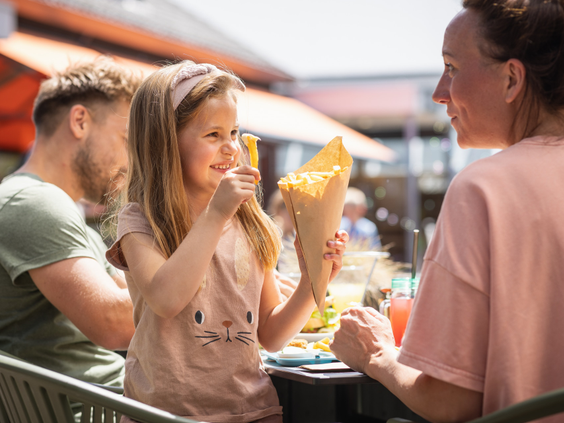 Meisje geniet van een puntzak friet op het terras van de snackbar op De Katjeskelder.