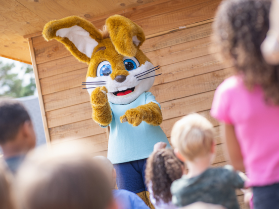 Kinderen kijken naar een poppenkastvoorstelling met Koos Konijn door het animatieteam op De Katjeskelder.