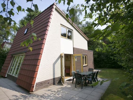 Een karakteristieke A-frame bungalow met een terras, gelegen in de groene en bosrijke omgeving van Bungalowpark Hoenderloo.