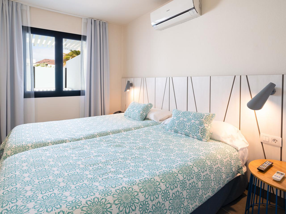 Tweepersoons slaapkamer in een bungalow van Relaxia Lanzasur Club met twee aparte bedden met blauw-wit beddengoed en airconditioning.