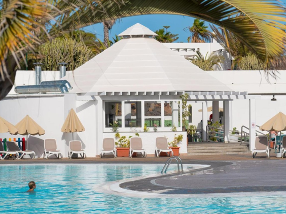De gezellige poolbar aan de rand van het zwembad van Relaxia Lanzasur Club, omringd door ligbedjes en palmbomen.