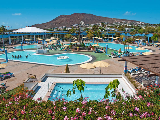 Het zwembadcomplex van Relaxia Lanzasur Club met uitzicht op de kenmerkende vulkanische bergen van Lanzarote.