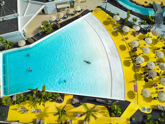 Luchtfoto van het golfslagbad in het Aqualava Waterpark met zout water, omringd door ligbedjes en parasols.