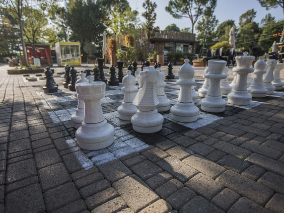 Een groot buitenschaakbord met levensgrote schaakstukken op een stenen plein op Camping Altomincio Family Park.