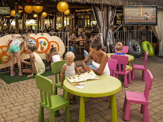 Kinderen eten aan kleurrijke kindertafels in restaurant Camping Altomincio Family Park Gardameer