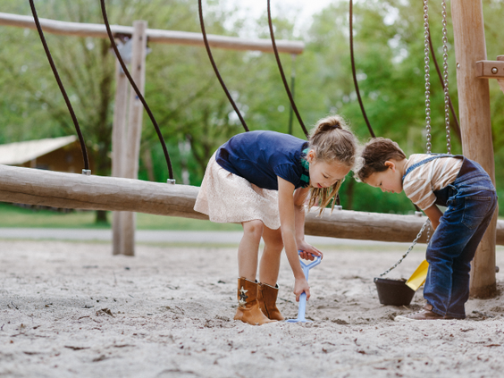 Twee kinderen spelen samen met emmertjes en schepjes in een grote zandbak op Camping Beekse Bergen.