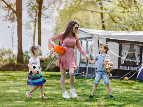 Een gezin met kinderen geniet van het buitenleven op een ruime, groene kampeerplaats op Camping Beekse Bergen.