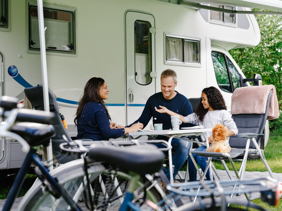 Een gezin ontbijt gezellig samen buiten aan een tafel voor hun camper op Camping Beekse Bergen.