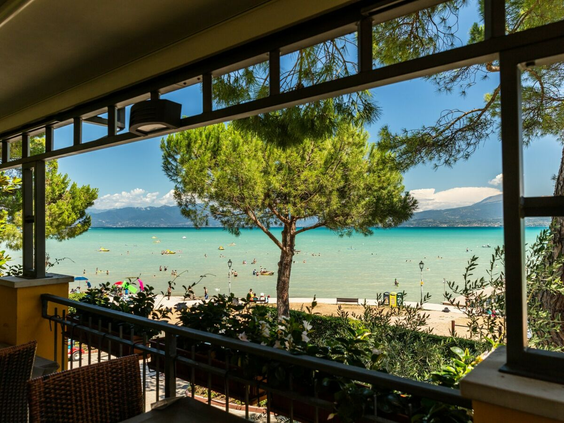 Uitzicht vanaf het terras van het restaurant op het strand en het Gardameer bij camping Bella Italia.