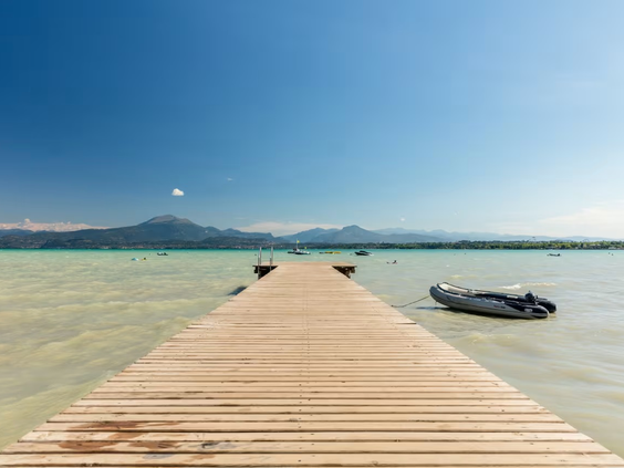 Houten aanlegsteiger in het Gardameer met uitzicht op de bergen, direct bij camping Bella Italia.