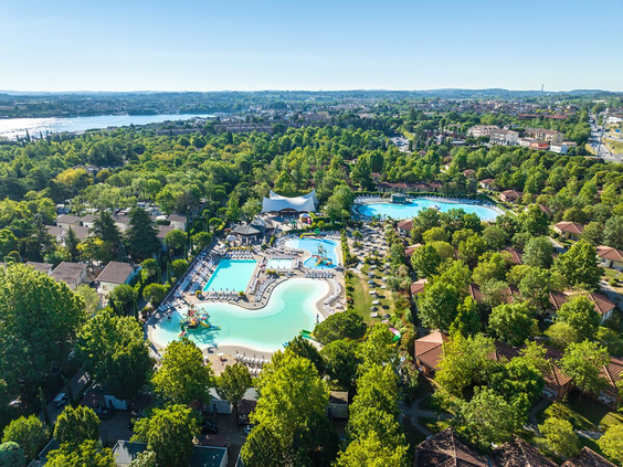 Luchtfoto Camping Bella Italia met zwembaden tussen groene bomen aan Gardameer
