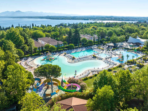 Panorama zwembaden Camping Bella Italia met Gardameer en bergen op achtergrond