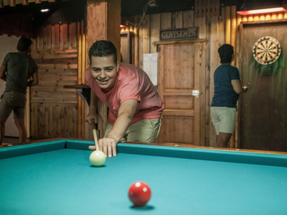 Jongen concentreert zich op een potje poolen in de recreatieruimte van Camping de Schatberg.