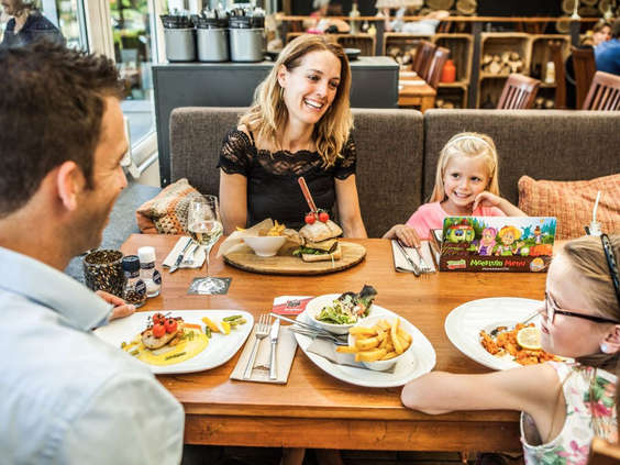Gezin geniet samen van een maaltijd in het familierestaurant van Camping de Schatberg.