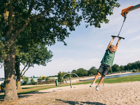 Jongen zoeft met hoge snelheid aan de kabelbaan over het zandstrand van Camping de Schatberg.