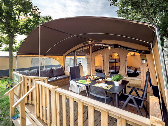 Gezellig ingerichte veranda van een safaritent met eettafel en loungebank op Camping de Schatberg.