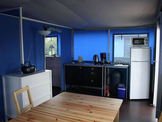 Het gezellige interieur van een trekkershut met een houten eettafel en een keukenblok op Knaus Campingpark Eschwege.