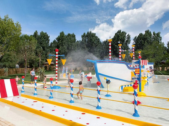 Kinderen spelen tussen de waterstralen en sproeiers van het spraypark op Camping Le Sérignan Plage, Frankrijk.
